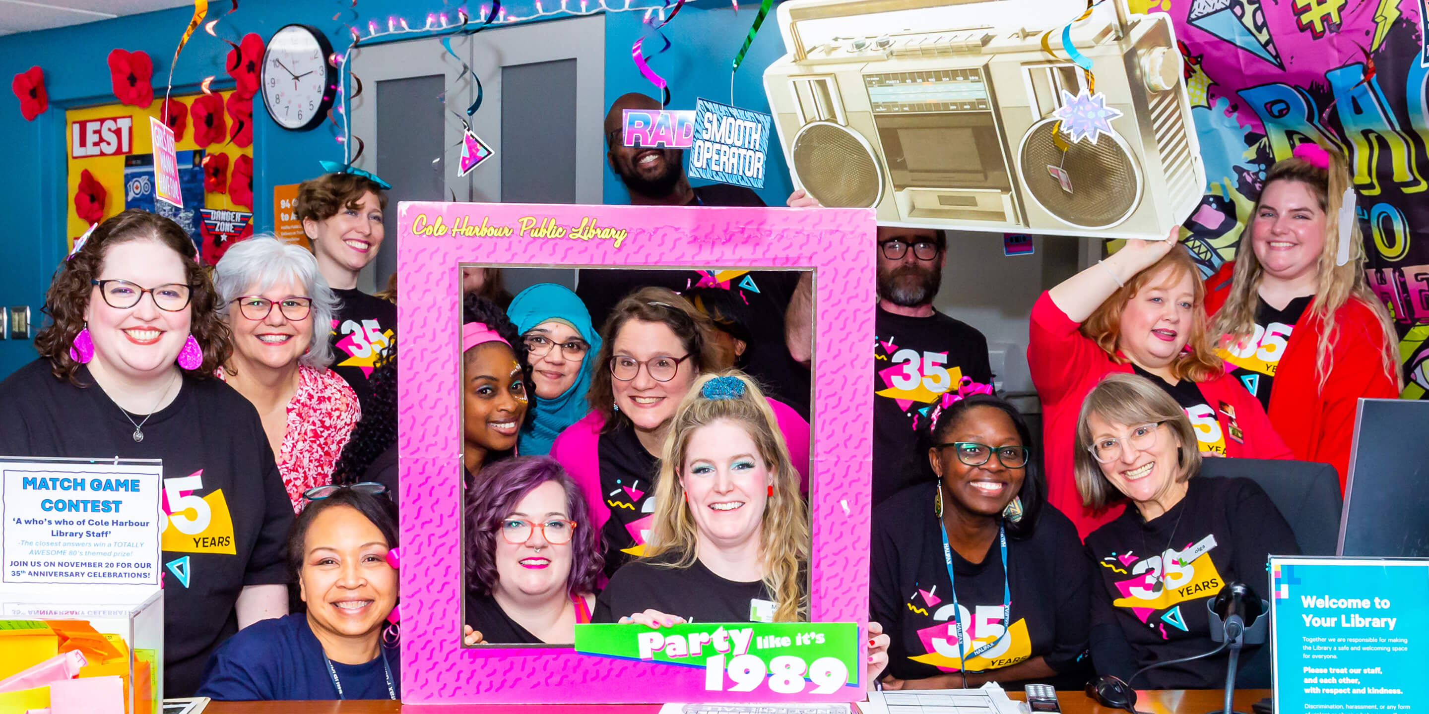 Library staff smiling for a group photo at the 80s themed anniversary.